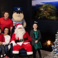 Little boy sitting on mom's lap with sister next to Santa and dad behind chair